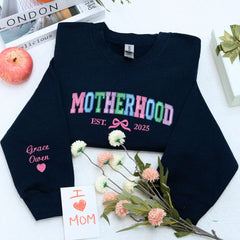 Motherhood Sweatshirt or Hoodie with Coquette Bow and Kids Names on Sleeve, Custom Embroidered Gift for Mother's Day